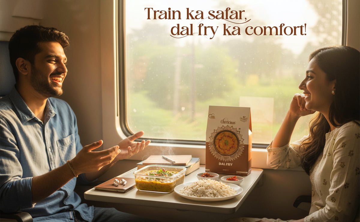 Two people enjoying a meal on a train with a box of dal fry in the foreground.