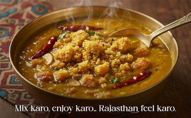 Steaming bowl of curry with a spoon, garnished with red chili peppers on a patterned fabric background.
