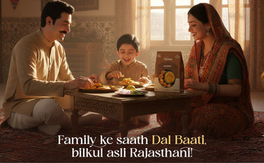 Family of three sitting around a table with a box of Dal Baati, in a warm indoor setting.