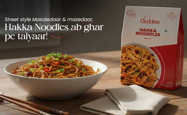 Bowl of Hakka Noodles with a box of Cherlicious Hakka Noodles on a wooden table.