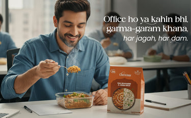 Man eating food from a container with a Chhota Bheem box on a desk, surrounded by colleagues in an office setting.