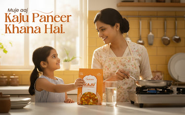 Woman and child in a kitchen with Kaju Paneer packaging, indicating a cooking or food product advertisement.