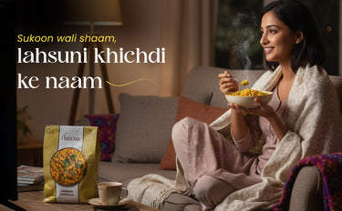 Woman sitting on a couch holding a bowl of food with a package of 'Khichdi' in the foreground.