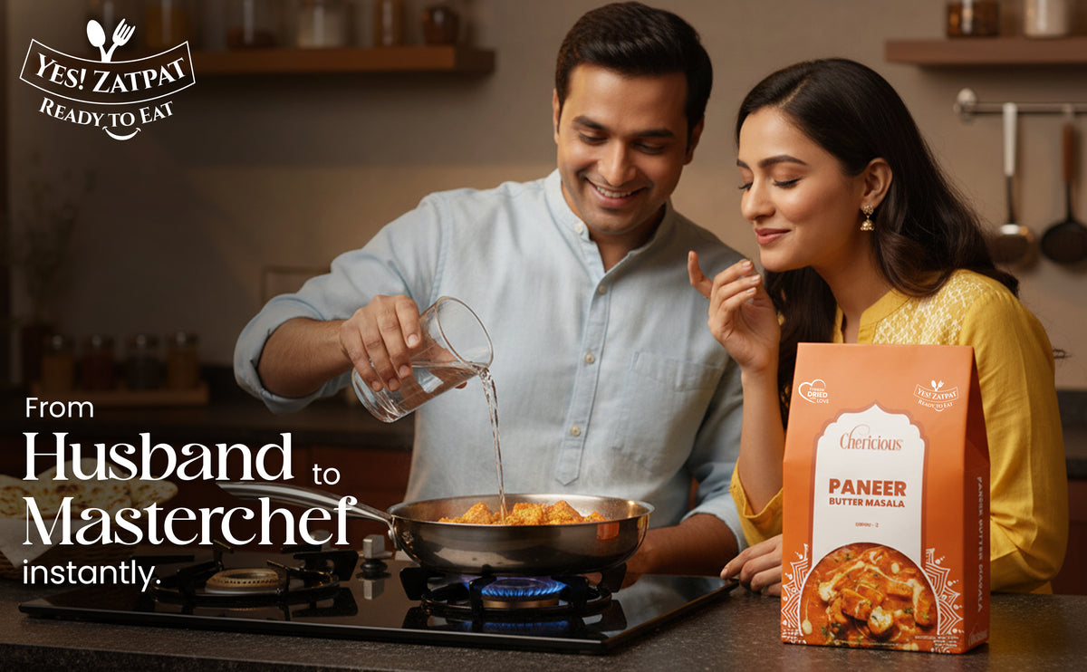 Man and woman cooking together with a box of Lushkart Paneer Butter Masala in a kitchen.