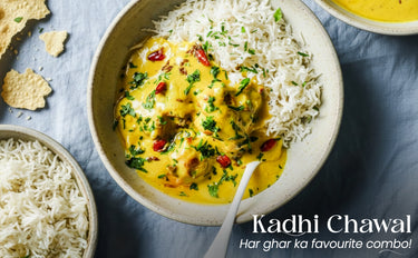 Bowl of Kadhi Chawal with rice and a spoon on a blue surface