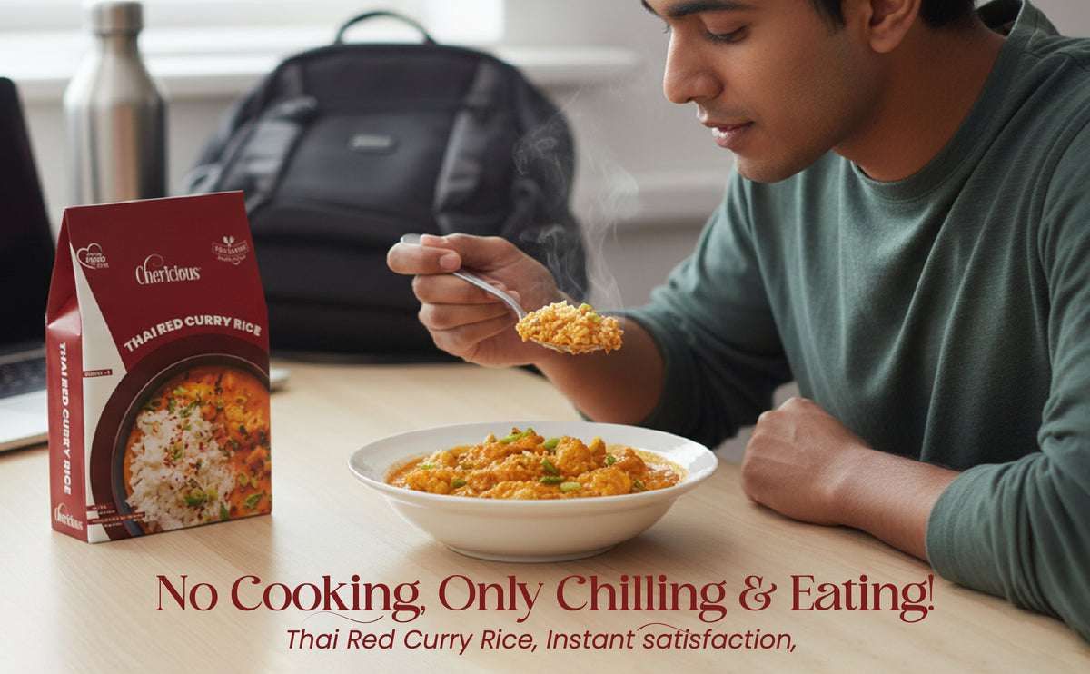 Person eating Thai Red Curry Rice with a box of the product on a table.