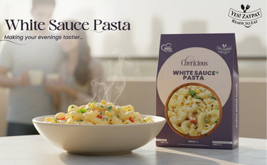 Bowl of white sauce pasta with a box labeled 'White Sauce Pasta' on a blurred background.